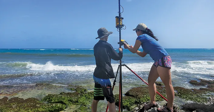 Students perform tests in Barbados with the ocean in the background.